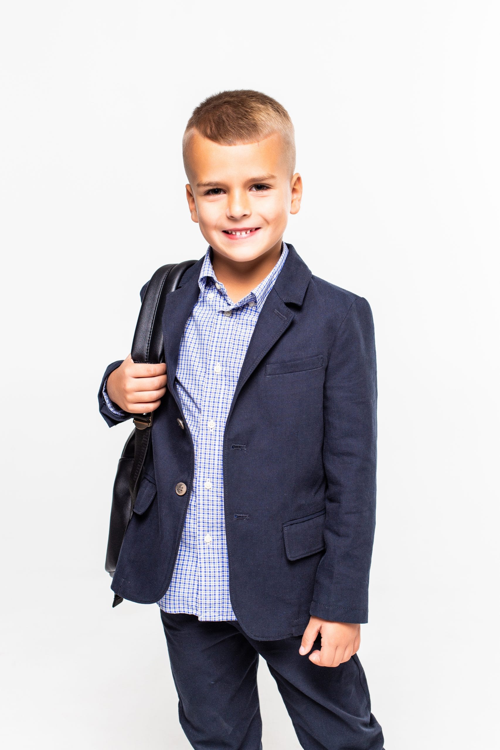 Jeune garçon portant un uniforme scolaire personnalisé composé d'un blazer bleu marine et d'une chemise à carreaux.